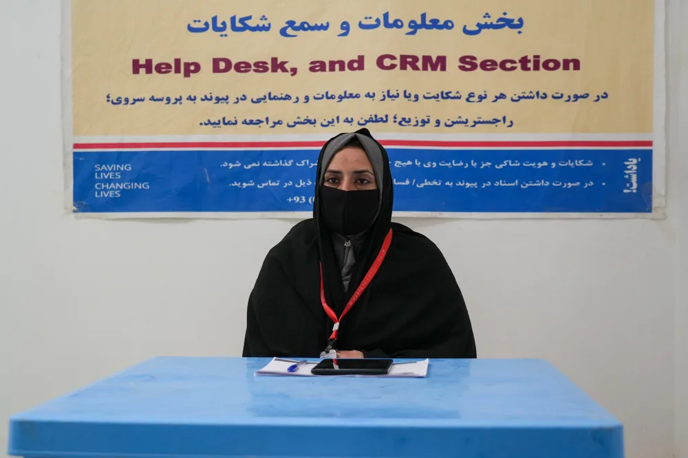 An FSCWEO staff member sits at a community help and feedback desk