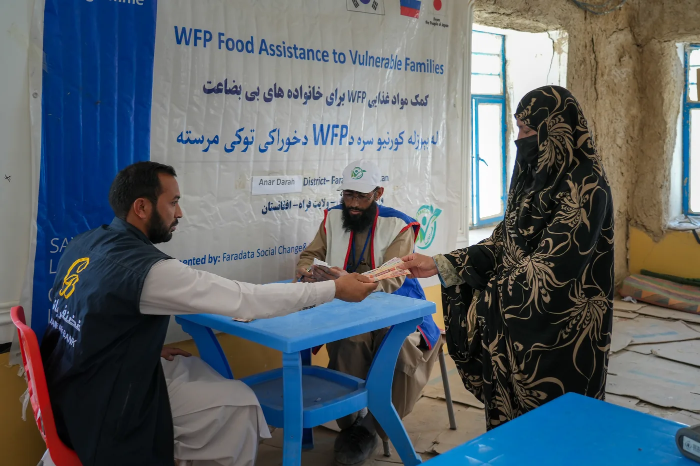A woman receives assistance at an FSCWEO and WFP desk in Farah