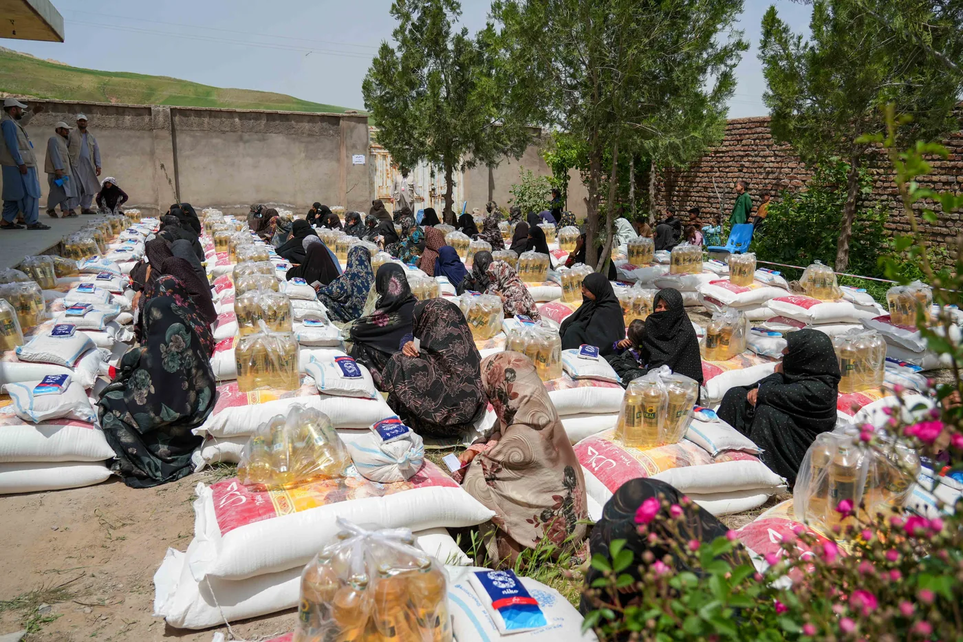 Women sit beside food packages at a distribution in Herat