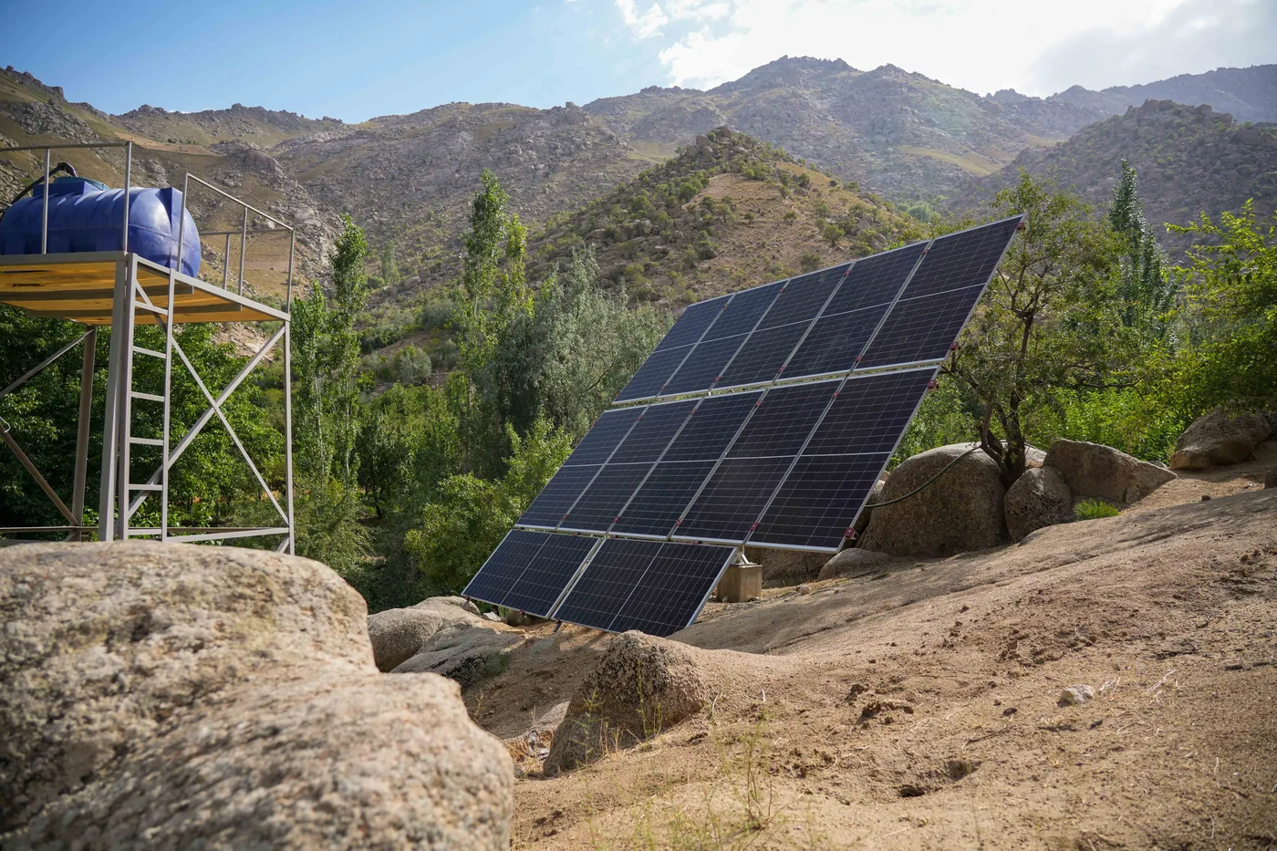 Solar panels and a water tank beside a greenhouse in Daikundi