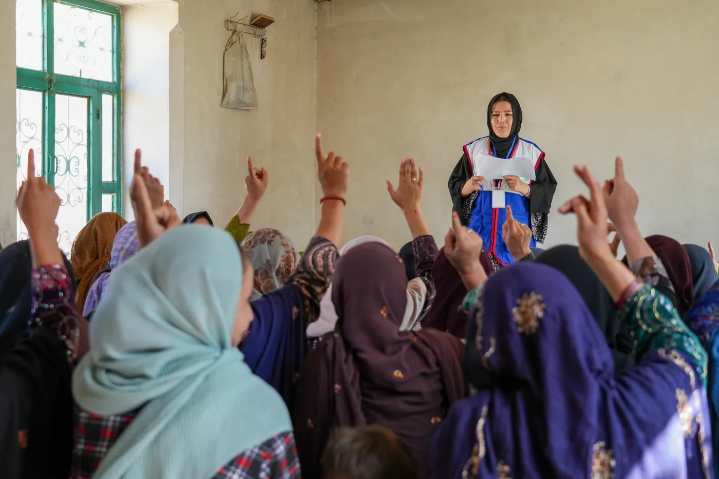Women raise their hands during an FSCWEO training session in Daikundi